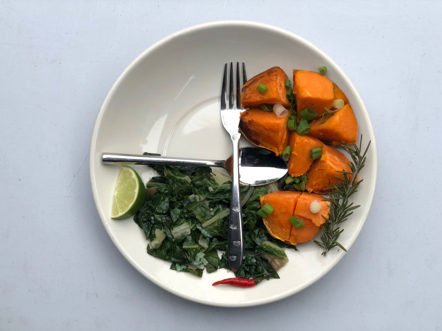 A Vivacity Acupuncture photograph showing a white plate with three-quarters filled with sweet potatoes, greens and herbs.